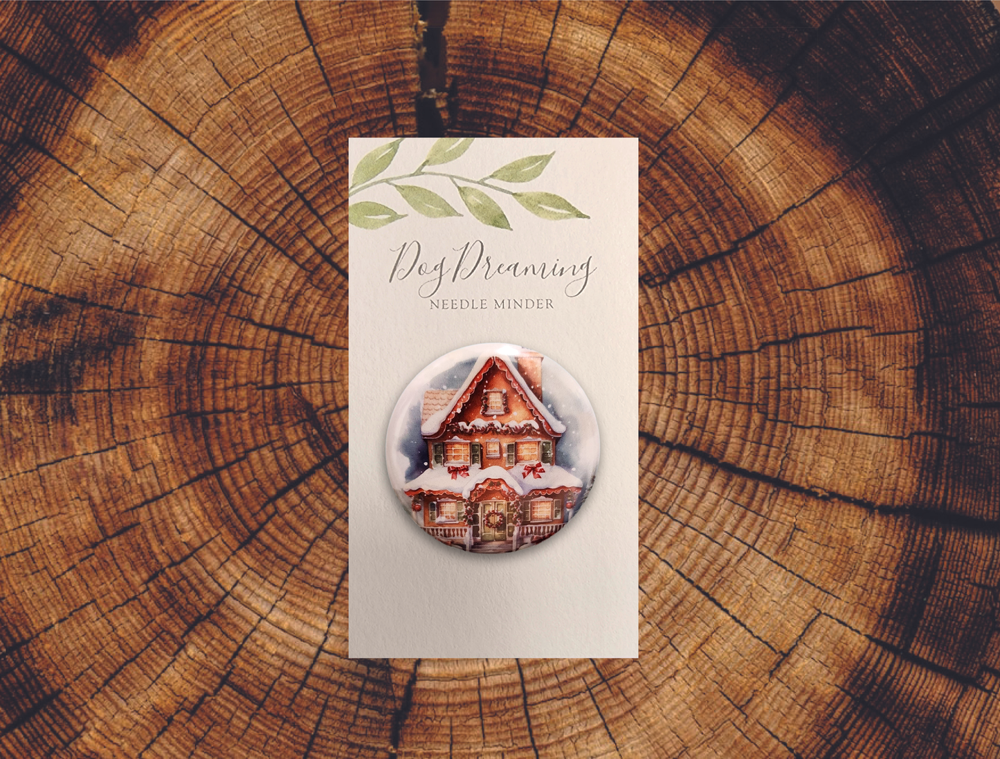 Cozy Christmas house needle magnet designed with frosted roof, wreath door, and glowing windows
